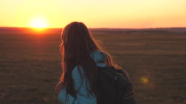 Una viajera camina con una mochila en la espalda y sonríe al atardecer en el cielo. Un adolescente en un viaje de campamento de vacaciones. Infancia en busca de aventuras desde la mañana hasta el amanecer. Amor por el — Vídeo de stock