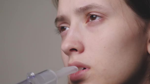 Människan andas djupt med en nebulisator för att behandla hosta, influensa, förkylningar. En ung flicka inhaleras med ett läkemedel mot bronkialastma eller allergier. Tonåringen behandlar sjukdomen hemma självisolering — Stockvideo