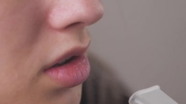 Gözlüklü kadın astım spreyini kullanıyor ve derin nefes alıyor. Nebuliser kullanan kızın portresi. Tedavide tıbbi araçların kullanılması teması.