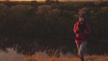Sırt çantalı mutlu bir turist gün doğumunda dağda yürür ve gülümser. Bölgede macera seyahati arayın. Yaşam biçimi olarak yaşam biçimi. Spor gezisindeki bir kadın. Doğada özgür bir adam.