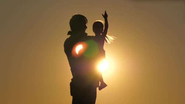 爸爸白天的轮廓与女儿在日落。女儿在父亲的怀里飞舞，胳膊伸到两边。这个女孩在她心爱的父母的怀里在空中翱翔。离职人数 — 图库视频影像