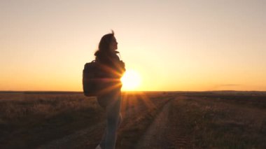 Sırt çantalı mutlu bir gezgin gün batımına gülümsüyor. Gün doğumunda turistik yürüyüşler. Güneşin parıltısında güzel, özgür bir kız. Gazeteye biraz ara ver.