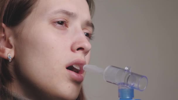 La niña inhala una solución para la inhalación de pulmones. Una mujer joven en cuarentena trata la tos inhalando vapor con medicamentos. Tratamiento de una persona en el hogar con equipo profesional para resfriados — Vídeo de stock