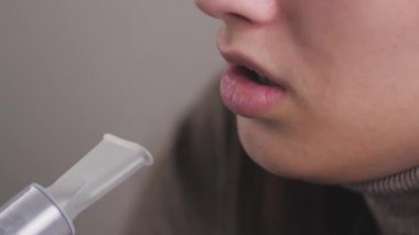Soğuk algınlığı için nebulizör öksürük şurubu soluyan bir kızın yakın çekimi. Astım tedavisi, grip alerjisi, solunum ve solunum yoluyla modern buhar yöntemleriyle ciğerler.