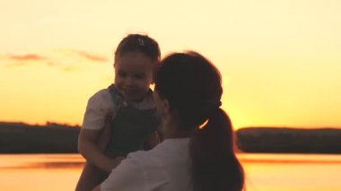 Mutlu anne gün batımında gökyüzünde kollarında neşeli bir çocuğun etrafında dönüyor. Anneler Günü. Anneler şafak vakti çocuğa aşık olurlar. Bebeğin için daha iyi bir gelecek için çabalıyorsun. Bir kadın onunla oynuyor.
