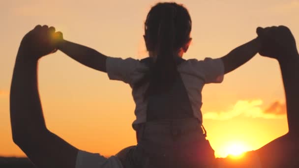 Gelukkig draagt papa een klein kind op zijn schouders met zijn handen omhoog bij zonsondergang in de lucht. Vaderdag. Een kind met een ouder droomt van vliegen tegen de achtergrond van de dageraad. Gezinsleven — Stockvideo