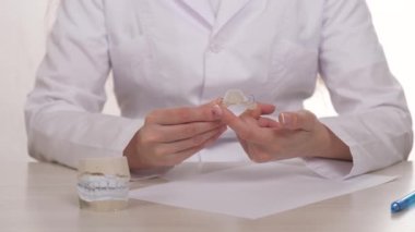 Ortodontist elinde diş ısırığını düzeltmek için bir çocuk plakası gösteriyor. Modern teknolojiyle dişçi kliniğinde güzel bir gülümseme yap. Hayatta sağlıklı bir gülümseme herkes için gereklidir.