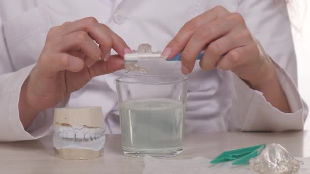 Врач-ортодонт показывает, как правильно мыть детские тарелки зубной щеткой. Современные технологии в стоматологических клиниках для коррекции укуса у подростков. Для красивой здоровой улыбки и даже ребенка — стоковое видео