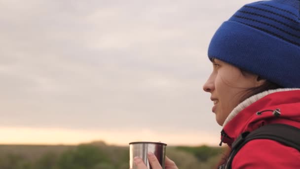 La chica bebe té de una taza sentada en una alta montaña y disfrutando de la naturaleza en el parque. Mujer viajera en busca de aventura. Relájate en la caminata. Excursiones de larga distancia. Explorador humano de — Vídeos de Stock