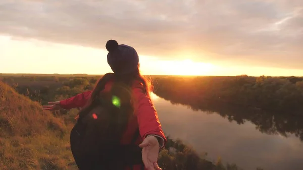 Een jong meisje met uitgestrekte armen voelt vrijheid bij zonsondergang. Vrouw avonturier op de achtergrond van de lucht. Onderzoek met een rugzak. Een weekendwandeling. Toerist op de grond. Levensvreugde in — Stockfoto