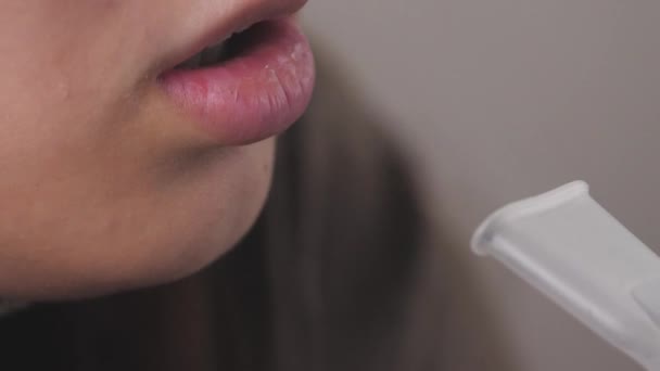 Dziewczyna wdycha roztwór do inhalacji płuc. Młoda kobieta objęta kwarantanną leczy kaszel wdychając parę za pomocą leków. Leczenie osoby w domu z profesjonalnym sprzętem do przeziębienia — Wideo stockowe