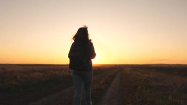 Sırt çantalı mutlu bir gezgin gün batımına gülümsüyor. Gün doğumunda turistik yürüyüşler. Güneşin parıltısında güzel, özgür bir kız. Gazeteye biraz ara ver.