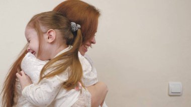 Mutlu anne küçük kızı kucaklıyor ve gülümsüyor. Ailesi olan bir aile hayatı. Anneler Günü. Anne, bebeğiyle kreşte oynuyor. Ebeveyn küçük çocuğu güldürür. Çocuk annesinin kollarında gülüyor.