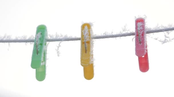 Mollette multicolore su una corda in hoarfrost appendere su una corda in inverno al di fuori nella neve — Video Stock