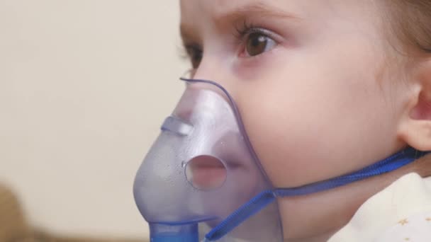 Un bébé mignon dans un masque respire par un inhalateur. Procédure d'inhalation à domicile. L'enfant reçoit un traitement respiratoire avec un nébuliseur. Traitez votre bébé pour le coronavirus à la maison. Un petit enfant — Video