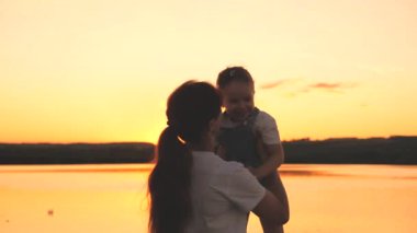 Mutlu anne gün batımında gökyüzünde kollarında neşeli bir çocuğun etrafında dönüyor. Anneler Günü. Anneler şafak vakti çocuğa aşık olurlar. Bebeğin için daha iyi bir gelecek için çabalıyorsun. Bir kadın onunla oynuyor.