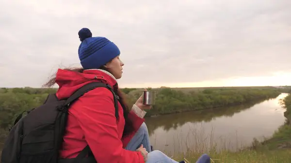 Het meisje drinkt thee uit een mok hoog op de berg en geniet van de natuur ontspant en kijkt in de verte. Een reiziger bij een stop in een cruisetour warmt zich op met een warm drankje. — Stockfoto