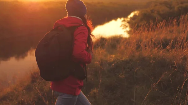 Chica feliz turista con una mochila camina por la montaña al amanecer y sonríe. Busca viajes de aventura por la zona. El camino de la vida como una forma de vida. Mujer en una caminata deportiva. Un hombre libre en la naturaleza —  Fotos de Stock