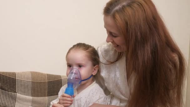 Mamusia wdycha małą dziewczynkę w masce z nebulizatorem w domu. Dziecko jest poddawane terapii oddechowej z użyciem nebulizatora. Lecz dziecko na koronawirusy w domu. Małe dziecko cierpi na — Wideo stockowe