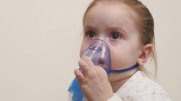 Un bébé mignon dans un masque respire par un inhalateur. Procédure d'inhalation à domicile. L'enfant reçoit un traitement respiratoire avec un nébuliseur. Traitez votre bébé pour le coronavirus à la maison. Un petit enfant — Video