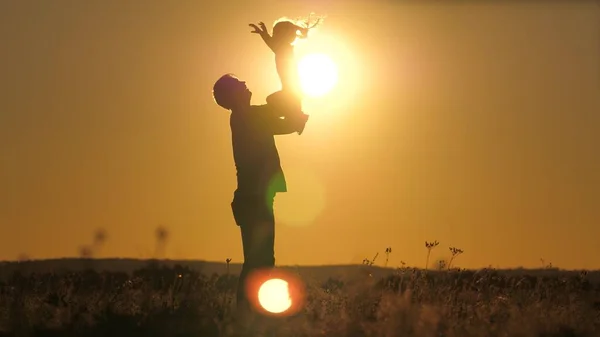 Silhouette dad throws happy little daughter into the sunset sky. Fathers day. The child wants to fly above the ground. A parent with a child plays at dawn. Family and childhood concept. Kid jumps on — Stock Photo, Image
