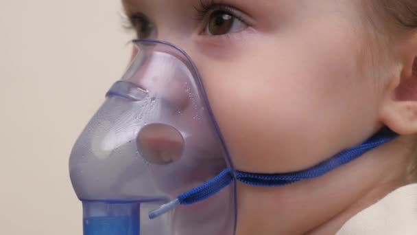Мила дитина в масці дихає через інгалятор. Процедура інгаляції вдома. Дитина отримує респіраторну терапію з туманністю. Лікуйте дитину від коронавірусу вдома. Маленька дитина — стокове відео