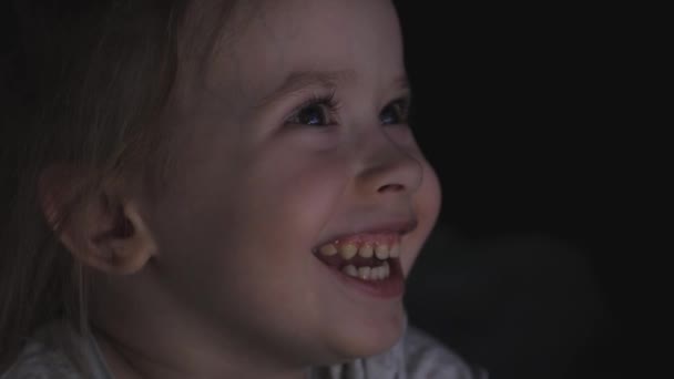 Retrato de un niño pequeño y lindo mientras ve la televisión. Una joven está viendo la televisión en el salón. El concepto de videojuegos, entretenimiento, emociones, familia. Niño viendo la televisión, primer plano de una — Vídeo de stock