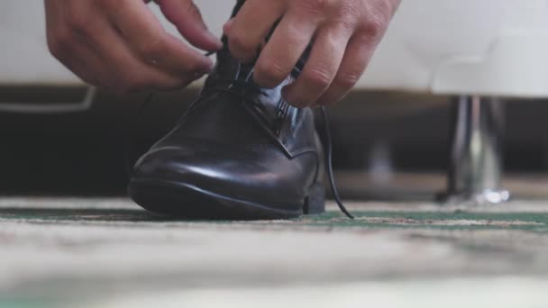 Pria itu mengikat shnzrki pada sepatu hitam. Memakai sepatu mens di pagi hari sebelum pergi bekerja. Tangan close-up — Stok Video