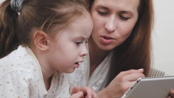 Szczęśliwa mama i dziewczynka patrzeć na wyświetlaczu tabletu i śmiać się przy wyborze zakupów. Zdalna komunikacja z krewnymi przez kamerę wideo gadżetu. Nauczanie dziecka online w domu — Wideo stockowe