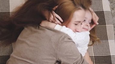 Mutlu anne, çocuk odasındaki kanepede yatarken bebeğe sarılıyor ve gülümsüyor. Anne ve kızı aile ilişkileri kavramında birbirlerini severler. Ebeveyn bakımı ve çocuğa bakımı. En sevdiğin bebeğin...