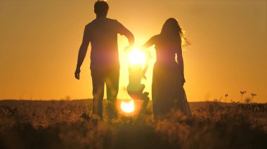Küçük bir çocuk anne ve babasıyla gökyüzünde parlak bir günbatımında yürür. Seyahat ederken ailenle gün doğumunu karşıla. Annen ve babanla yürüyüşe çık. Çocuk ve sevgi dolu ebeveynler parkta yürürler.