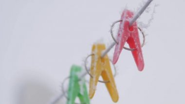 Kış ayazında ipte çok renkli mandallar asılı. Kışın dışarıda, karda.