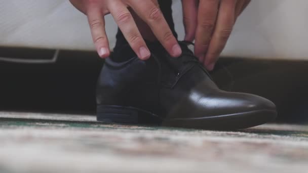 The man is tying the shnzrki on black shoes. Putting on mens shoes in the morning before going to work. Hands close-up — Stock Video