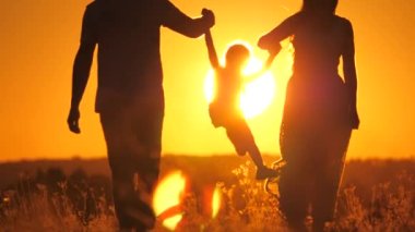 Anne, baba ve küçük çocuk gün batımında ebeveynlerin elinde süzülüyor, büyük güneşte aile seyahati, anne baba ve çocuk gün doğumunda, mutluluk konsepti, takım çalışması, tatil tatili, bebek yetiştirme