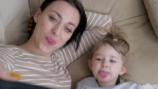 Äkta närbild av neo mor och hennes barn gör en selfie eller videosamtal till far eller släktingar i en säng. Skjuten i 8K. Begreppet teknik, ny generation, familj, anslutning, föräldraskap — Stockvideo
