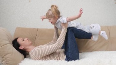 Mutlu, güzel, sağlıklı, sağlıklı bir aile. Küçük, tatlı bir kız çocuğu kaldırıyor. Evdeki kanepede uçuyor.