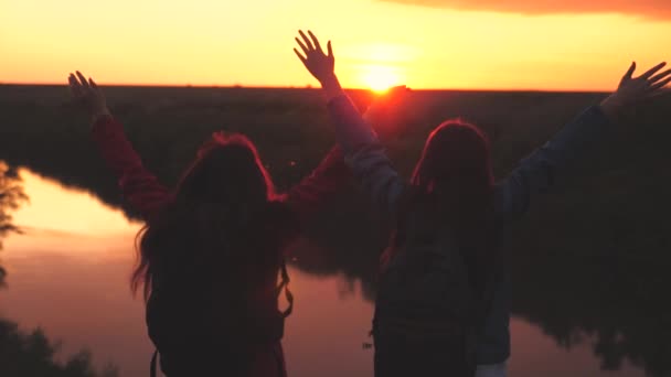 Niñas felices viajeros están saltando en una hermosa puesta de sol en el cielo de la noche con las manos en alto, la libertad y la sed de aventura, adrenalina femenina, lograr victorias para los objetivos establecidos, cumplir con el — Vídeos de Stock