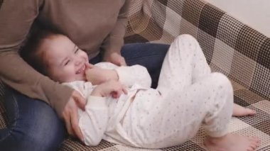 Annesiyle mutlu çocuk kanepede yatıp gülerken oynuyor. Ailedeki küçük çocuk. Anne bakımında eğlenceli bir çocukluk. Doğum iznindeki kadın. Çocuk odasında bir bebek var. Ebeveyn bakımı ve