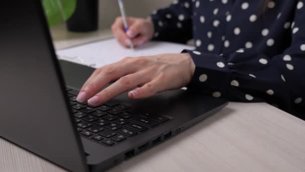 Zakenvrouw drukt een document af op een laptop en schrijft verslagen in een tablet, het werk van een kantoormedewerker op kantoor aan een computer op tafel, een meisje vult een sollicitatieformulier in, houdt dossiers bij — Stockvideo