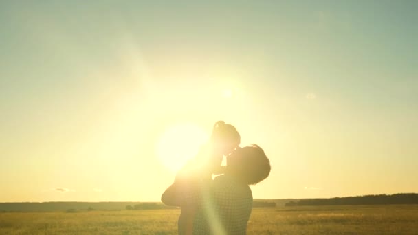 お父さんは日没時に幸せな子供を空に投げつける。父親の娘は太陽のぎらぎらとゲーム機を再生空気中で上昇彼の腕の中で飛ぶ。子供は父親と一緒に喜んでる — ストック動画