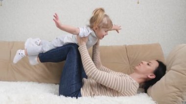 Mutlu, güzel, sağlıklı, sağlıklı bir aile. Küçük, tatlı bir kız çocuğu kaldırıyor. Evdeki kanepede uçuyor.