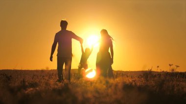 Küçük bir çocuk anne ve babasıyla gökyüzünde parlak bir günbatımında yürür. Seyahat ederken ailenle gün doğumunu karşıla. Annen ve babanla yürüyüşe çık. Çocuk ve sevgi dolu ebeveynler parkta yürürler.