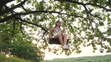 Mutlu genç kız havada yüksekten sallanıyor, yükseliyor ve uçuyor kahkahalar atıyor, uçuyor, çocukluğunda sokaklarda oyun oynuyor, neşe ve adrenalinle nefes kesiyor.