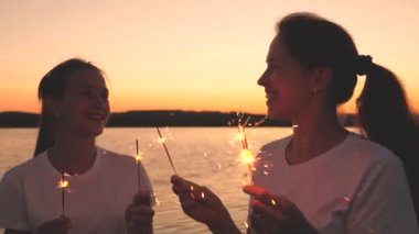 Mutlu kızlar gün batımında gökyüzünde maytap yakar ve gülerler. Gençler güneşin doğuşunu güzel ışıklarla selamlıyor. Kız arkadaşlar seyahat eder. Tatillerde dinlenin. Doğum gününü neşeyle kutluyorsun.