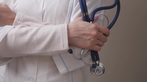 Μια γυναίκα γιατρός με λευκό παλτό κρατά ένα στηθοσκόπιο στα χέρια της, θεραπεία και εξέταση σε μια κλινική, ιατρική συνοδοί κάνουν μια εξέταση σε ένα νοσοκομείο για την υγεία — Αρχείο Βίντεο