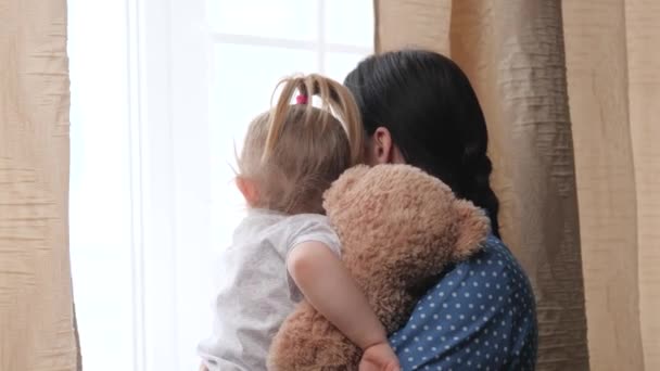 Une mère calme un petit enfant tenant et secouant un ours en peluche avec un ours en peluche, un enfant bouleversé est à la recherche de soutien dans une étreinte de mère, le concept de relations familiales, une nounou femme prend — Video