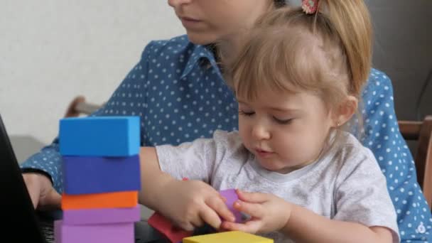 Žena na volné noze pracuje doma u počítače s malým dítětem v náručí, matka a dítě tráví čas spolu, dítě hraje s kostkami, život dospělého je on-line na sociálních sítích — Stock video