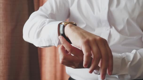 En man tittar på urtavlan på sin hand, för att kontrollera tiden, att vara sen till jobbet på morgonen, affärsmannen är punktlig, affärsplanen är i tid — Stockvideo