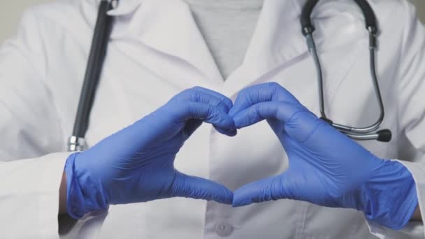 Een arts in blauwe handschoenen toont zijn hart, een cordioloog voor een gezonde uitstroom van bloed, de diensten van een therapeut in ziekenhuizen met de beste specialisten, het is tijd om het lichaam te onderzoeken voor — Stockvideo