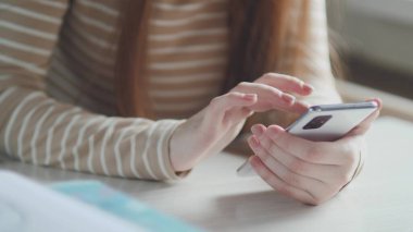 Kapalı bir iş kadını ev telefonunda mesaj yazıyor, genç bir kız telefonda sohbet ediyor. Akıllı telefon kullanarak genç kadın ellerini kapat.